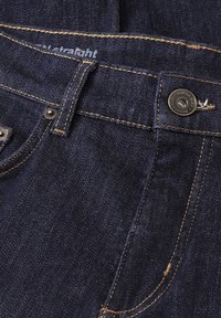 Donkerblauwe denim jeans met gouden stiksels, een zilveren knoop en een klassiek vijf-pocket ontwerp met een soepele textuur.