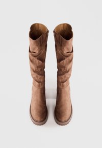 Cizme maro peste genunchi din suede moale, cu un design lejer, vârf rotund și fermoar lateral pentru o îmbrăcare ușoară.