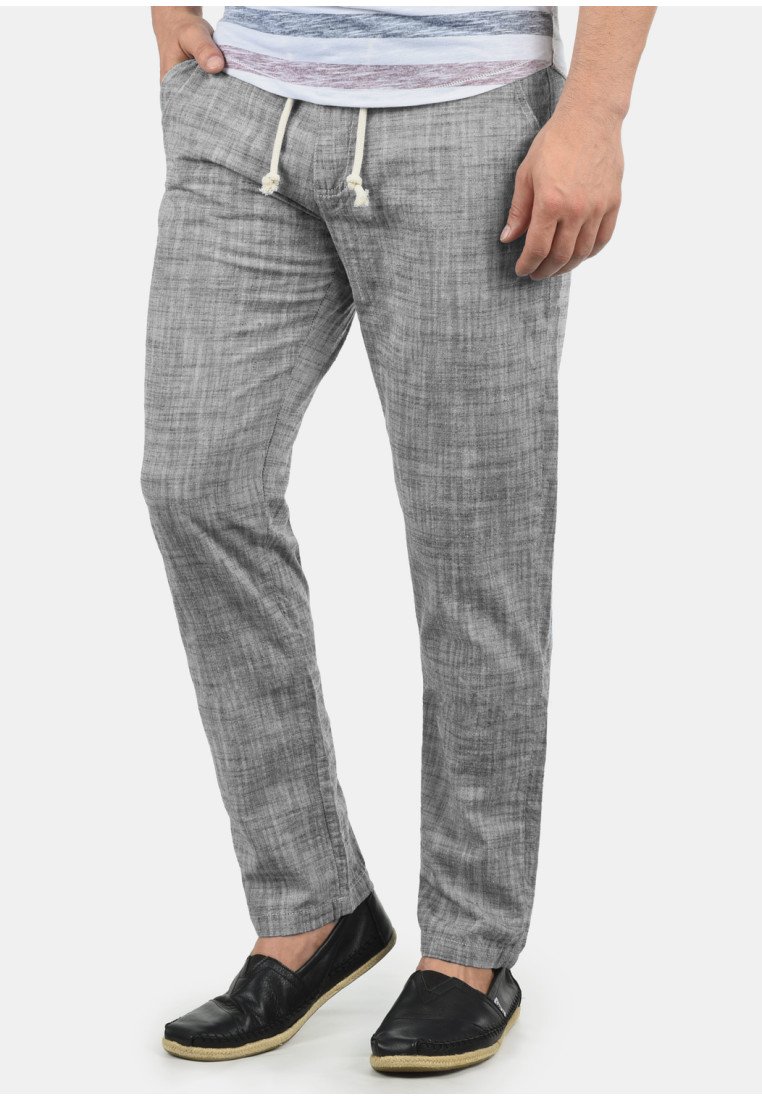 Grå linbyxor med en avslappnad passform, med en dragsko i midjan och subtil struktur. Kombinerade med svarta slip-on-skor.