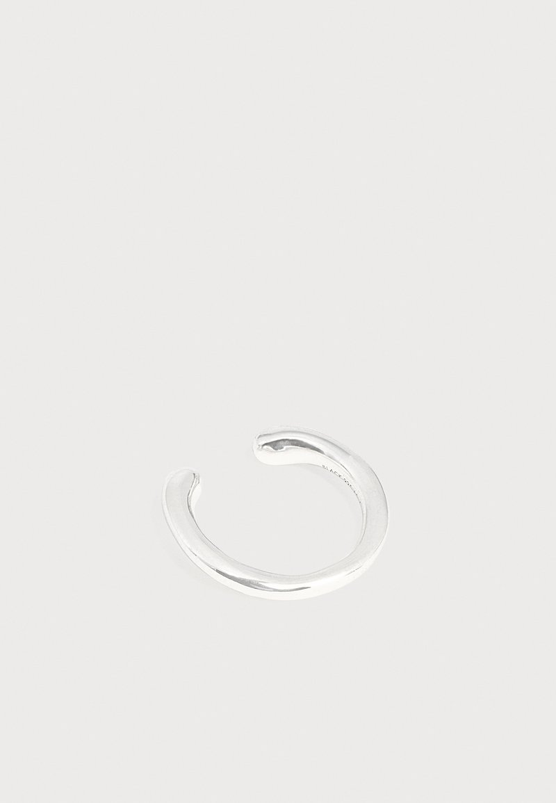 Bague manchette ouverte minimaliste en argent brillant avec des bords arrondis lisses sur un fond clair uni.