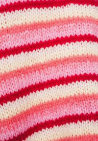 Πλεκτό ύφασμα με εναλλασσόμενες ρίγες σε αποχρώσεις κόκκινου, ροζ και λευκού. Η υφή είναι μαλακή και χνουδωτή με ελαφρώς άνιση πλεκτή υφή.