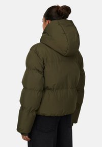 Giacca imbottita verde oliva con cappuccio, caratterizzata da un design trapuntato, polsini elasticizzati e una silhouette cropped. Tessuto morbido e leggero.