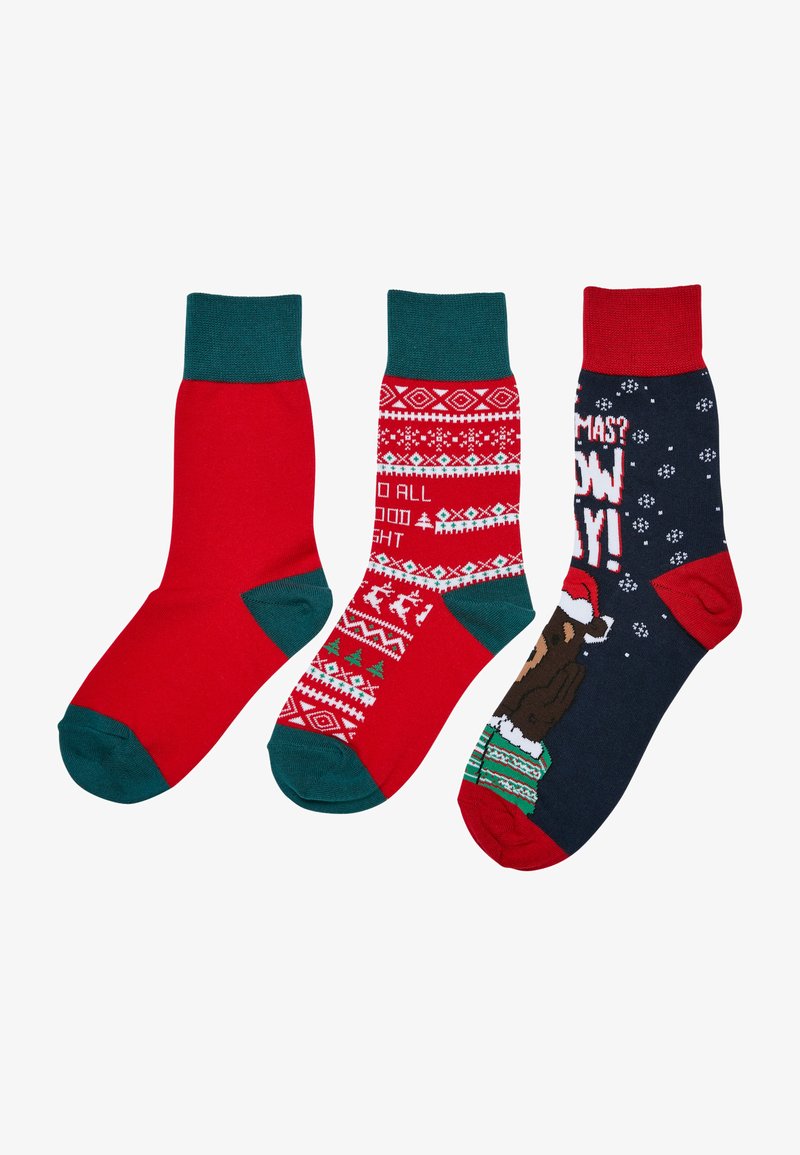 Conjunto de tres pares de calcetines: uno rojo liso, uno rojo con patrones festivos y uno azul marino con un oso en un gorro de Santa. Hechos de un tejido suave.