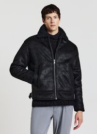 Giacca nera in ecopelle con finitura testurizzata, dotata di collo in shearling, chiusura a zip, tasche laterali e polsini a coste.