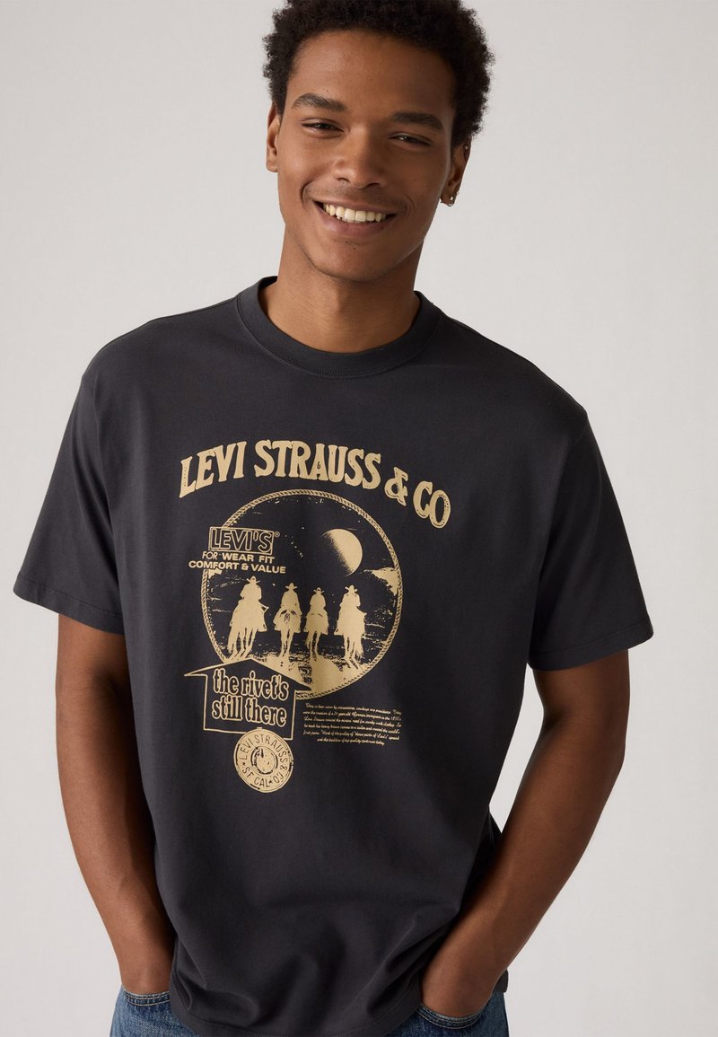Schwarzes Baumwoll-T-Shirt mit Rundhalsausschnitt, das einen großen goldenen Grafikdruck von Reitern und Text von Levi Strauss & Co. zeigt.