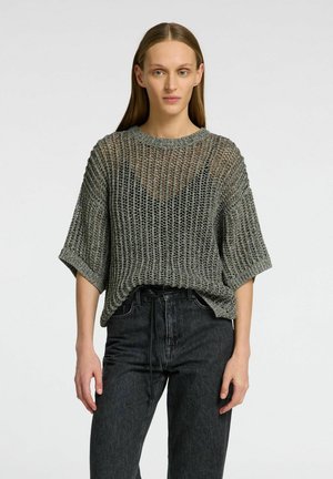 Grå strikket sweater med en afslappet pasform og korte ærmer, der har et tekstureret, åbent vævdesign. Sammen med mørke denimbukser.