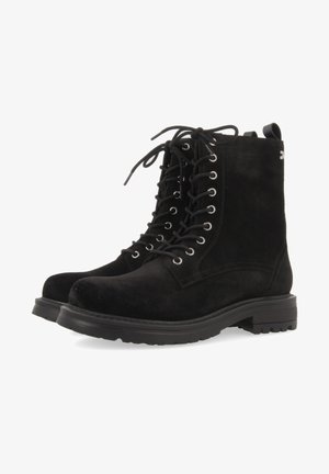Black suede lace-up boots with round toe, silver eyelets, flat rubber sole, and pull tab at the back for easy wear.