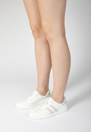 Baskets blanches en cuir, avec une surface texturée, des rayures gris clair et un accent de talon gris doux. Design à lacets.