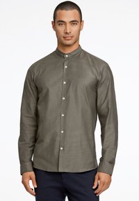 Camisa de manga larga de color verde oscuro con cuello mao, cierre frontal de botones y textura suave. Presenta botones en contraste y un corte ajustado.