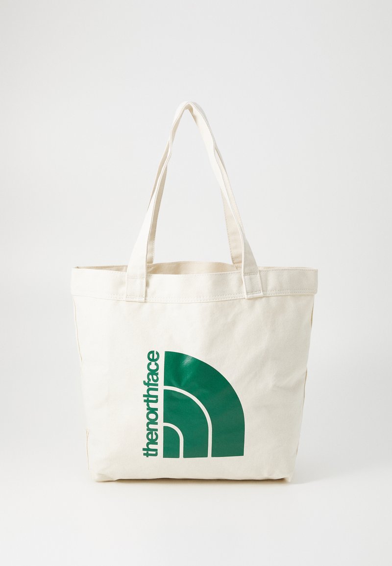 Borsa tote in tela di un beige chiaro con logo verde che presenta un design a mezz'arco. Manici robusti per il trasporto. Texture liscia, design semplice.