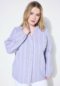 Camisa de botón en color púrpura claro con rayas verticales y patrones florales, que cuenta con mangas largas, escote en V y un corte relajado.