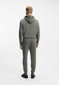 Hooded sweatshirt and jogger set in muted green, featuring ribbed cuffs and waistband, soft fabric, and black sneakers.
