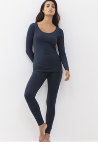 Námořnicky modrý dlouhý rukáv s výstřihem do lodičky spojený s odpovídajícími těsnými legínami. Hladká textura, bezešvý design, minimalistický styl.