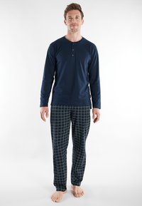 Navy long-sleeve henley shirt with three buttons paired with plaid pajama pants in navy and green. Soft fabric, relaxed fit, casual design.