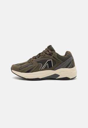 Atletyczny sneaker w kolorze oliwkowej zieleni z siateczkową tkaniną, czarnymi i beżowymi akcentami, grubą beżową podeszwą i wiązaniem na sznurówki, widoczny z boku.