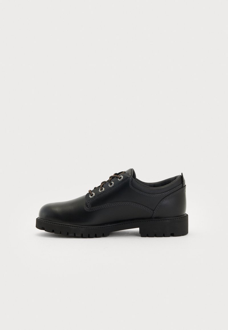 Black leather shoes with a rounded toe, lace-up design, and rugged rubber sole. Features subtle stitching and a smooth texture.