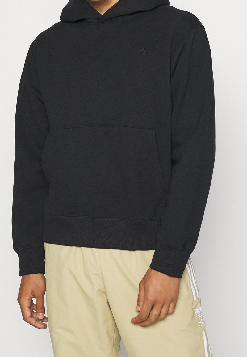 Svart huvtröja i bomullsblandning med framficka och ribbade ärmar. Har en liten, ton-i-ton logotyp på bröstet.