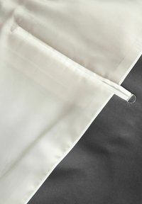 Suurem lähedalt vaade valgele kangale, mis on õmmeldud halli kanga külge, et hoida posti või varrast.