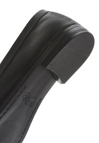 Scarpa nera in pelle con una texture liscia, suola piatta elevata e punta rotonda. Presenta un intaglio distintivo sul bordo posteriore del tallone.