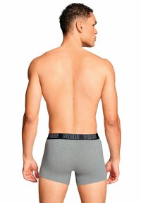 Boxer in cotone grigio con una fascia in vita nera con logo Puma, che mostra un design aderente e una texture morbida. Il modello è mostrato di spalle.