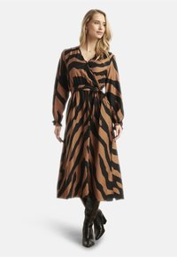 Wikkeljurk in bruin en zwarte zebraprints, met lange mouwen, een strik taille en een vloeiende rok. Gemaakt van zachte stof met een ontspannen pasvorm.