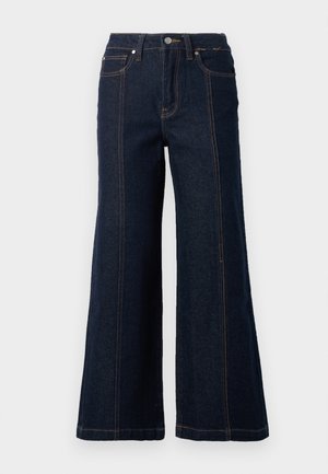 Bredde jeans i mørk denim. Har høy midje, to frontlommer og kontrasterende oransjefarger sømmer langs sømmene.