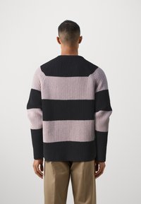 Pulover din tricot cu textura canelată, având dungi orizontale în negru, roz și gri închis. Mâneci lungi și guler rotund cu o croială lejeră.