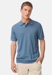 Polówka z krótkim rękawem w jasnoniebieskim kolorze, z klasycznym kołnierzykiem, trzema guzikami oraz subtelną fakturą. Doskonale uzupełnia casualowy styl.