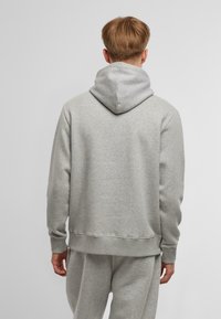 Felpa grigia con cappuccio, dal taglio comodo, realizzata in morbido materiale misto cotone. Presenta un cappuccio regolabile con lacci e polsini a coste.