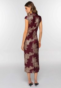 Vestido burdeos con un patrón texturizado en dorado. Diseño ajustado con mangas tipo manga corta y largo midi, con una abertura lateral en el dobladillo.