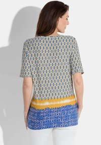 T-shirt met korte mouwen in witte, gele en blauwe patronen; heeft een geometrisch ontwerp met een geleidelijke kleurverloop bij de onderrand.