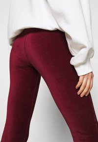 Burgundy corduroy leggings med en figurnära design, med vertikala ribbor, midjehöjd och en mjuk känsla. Stylad med en vit sweatshirt.