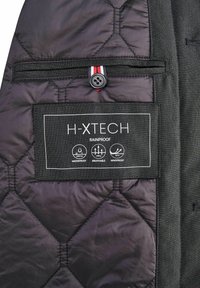 Zwarte gewatteerde jas met H-XTECH-label. Heeft waterafstotende, ademende en winddichte eigenschappen. Bevat een knop en gestreepte accenten.