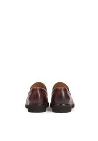 Mocassins en cuir marron avec une finition lisse et un embout arrondi. Couture notable et une semelle en caoutchouc noir texturée et basse.