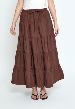 Brown tiered maxi skirt with a drawstring waist worn with a white top and black open-toe sandals on a white background.