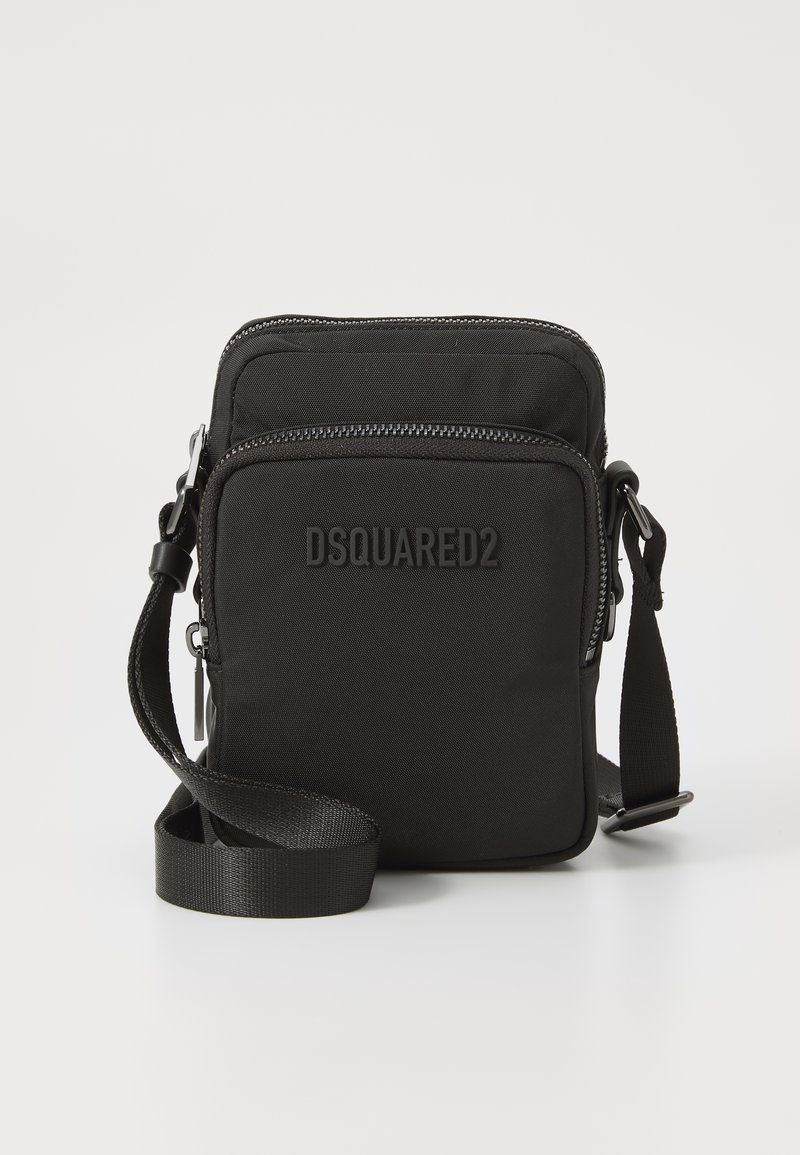 Black nylon crossbody bag with two zippered compartments, adjustable strap, and embossed logo on front. Compact rectangular design.