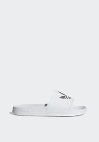White slide sandal with an open toe, featuring a wide strap with cutouts and three black stripes. Textured sole with Adidas logo.