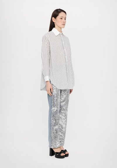 Gestreept overhemd met een witte kraag, gecombineerd met zilveren paillettenbroek en blauwe jeans, aangevuld met zwarte hoge hakken sandalen.