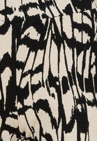 Tyg i svart och vitt med ett abstrakt mönster och en texturerad väv, visad i en närbild.