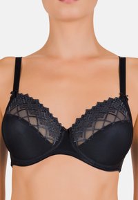 Soutien-gorge noir avec une partie inférieure lisse et une partie supérieure transparente et à motifs présentant des designs géométriques. Bretelles ajustables et détail central en forme de nœud.