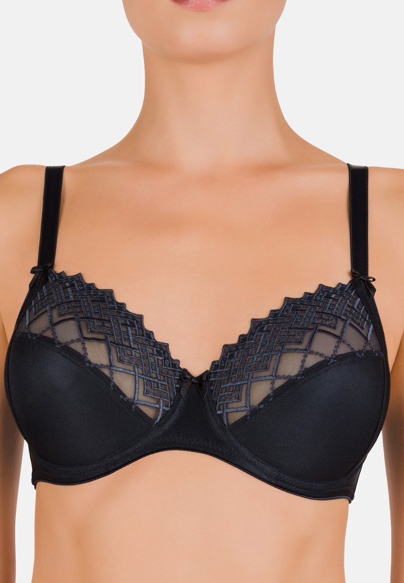 Soutien-gorge noir avec une partie inférieure lisse et une partie supérieure transparente et à motifs présentant des designs géométriques. Bretelles ajustables et détail central en forme de nœud.