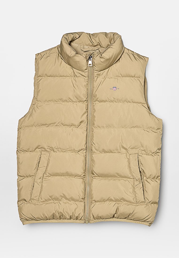 Beige padded vest with a high collar, front zipper, and two side pockets. Features quilted texture and a small logo on the chest area.