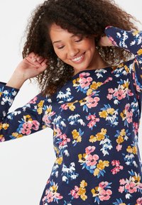 Květinová dlouhá rukávová blůza v námořnické modři, zdobená růžovými, žlutými a bílými květinami. Měkká látka, kulatý výstřih a uvolněný střih.