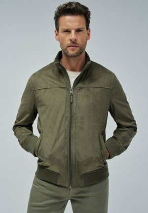 Chaqueta verde oliva hecha de un material similar a ante, con cierre de cremallera en la parte frontal, cuello alto, puños acanalados y dobladillo. Presenta bolsillos laterales con una textura suave.