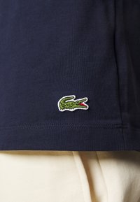 Navy cotton t-shirt with a round neckline, featuring a green and white embroidered crocodile logo on the lower left side.