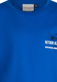 Niebieska bawełniana koszulka z okrągłym dekoltem, krótkimi rękawami i białym nadrukiem graficznym z nazwą marki i tekstem z przodu.