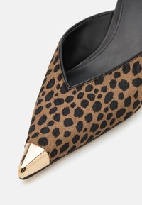 Escarpin à bout pointu en imprimé léopard avec un dessus texturé marron et noir, doté d'un bout métallique doré brillant et d'un intérieur noir élégant.