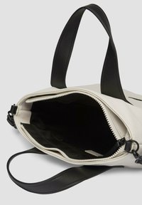 Biała skórzana torebka z czarnymi uchwytami, zamknięcie na zamek i miękkie czarne wykończenie. Posiada przestronną wnętrze i gładką fakturę.