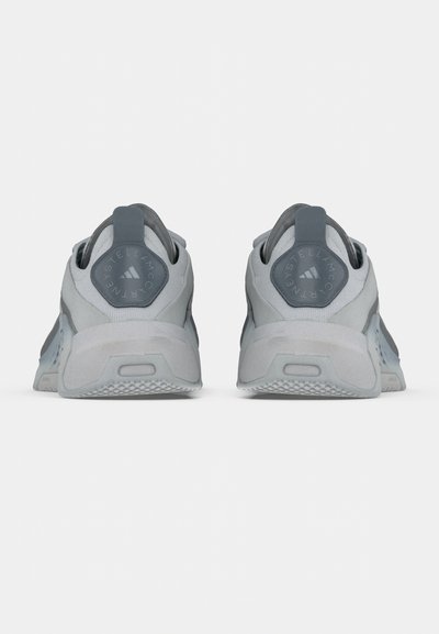 Γκρι αθλητικά παπούτσια με επάνω μέρος από μαλακό δίχτυ, στρογγυλεμένη φτέρνα και υφασμένο πέλμα. Η όψη από πίσω δείχνει λεπτομέρεια λογότυπου και ταιριαστά στοιχεία.