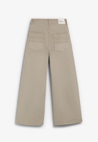 Pantalones beige de pierna ancha con textura suave, que presentan costuras decorativas en los bolsillos traseros y una etiqueta en la cintura.
